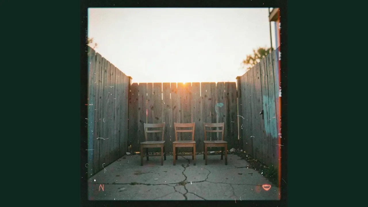 Three empty chairs face a sunset, surrounded by a dark forest green frame.